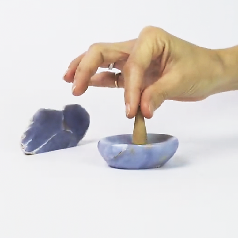 Hand placing a carved stone cone into the angelite catchall dish