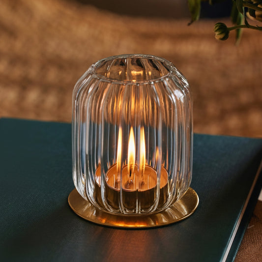 Kira glass lantern with a lit tealight on its brass base