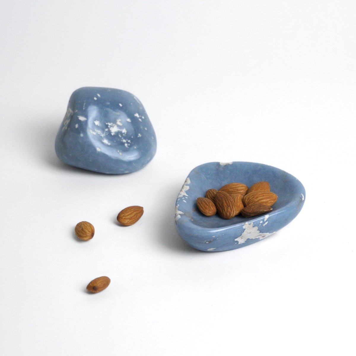 Blue angelite catchall holding almonds beside a raw angelite pebble