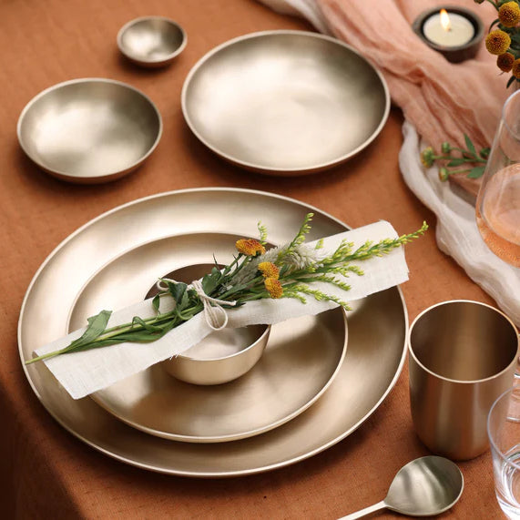 Kansa bronze platter laid for a table with a bowl, napkin and greenery