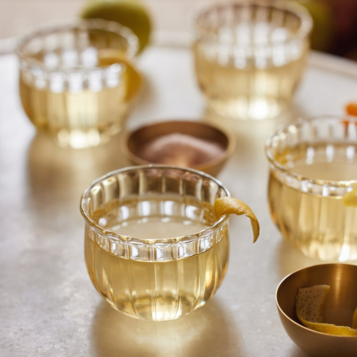 Kira glass cups with citrus peel on a pale stone counter