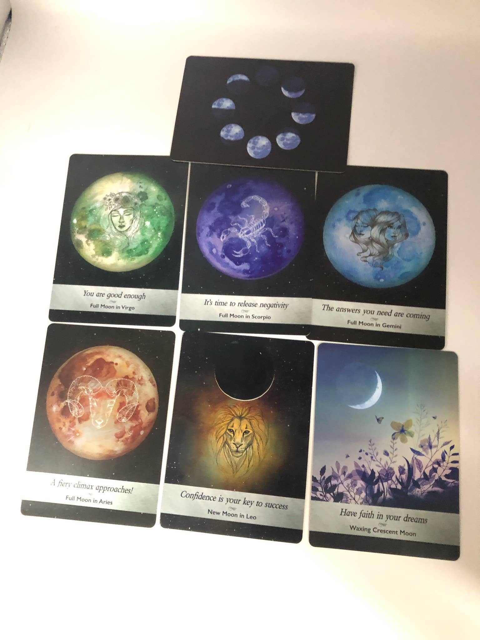 Six Moonology oracle cards laid out in a spread, each showing a different moon phase