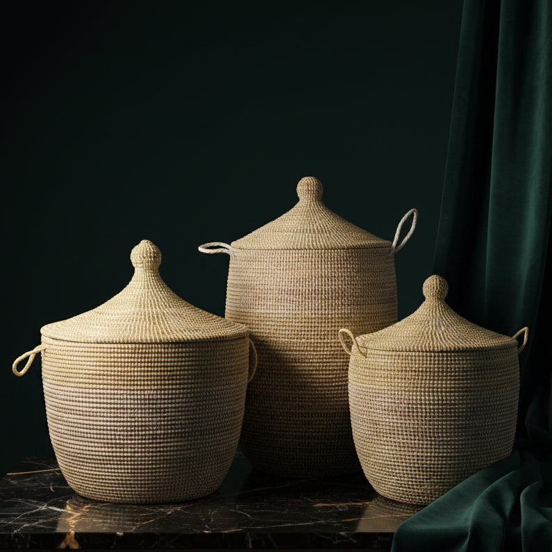 Three handwoven two-tone baskets with lids in graduated sizes on dark marble