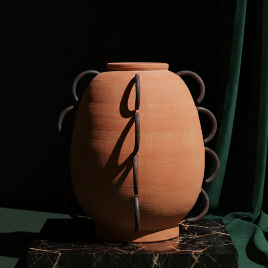Ella terracotta vessel with looping iron handles on dark marble against green velvet