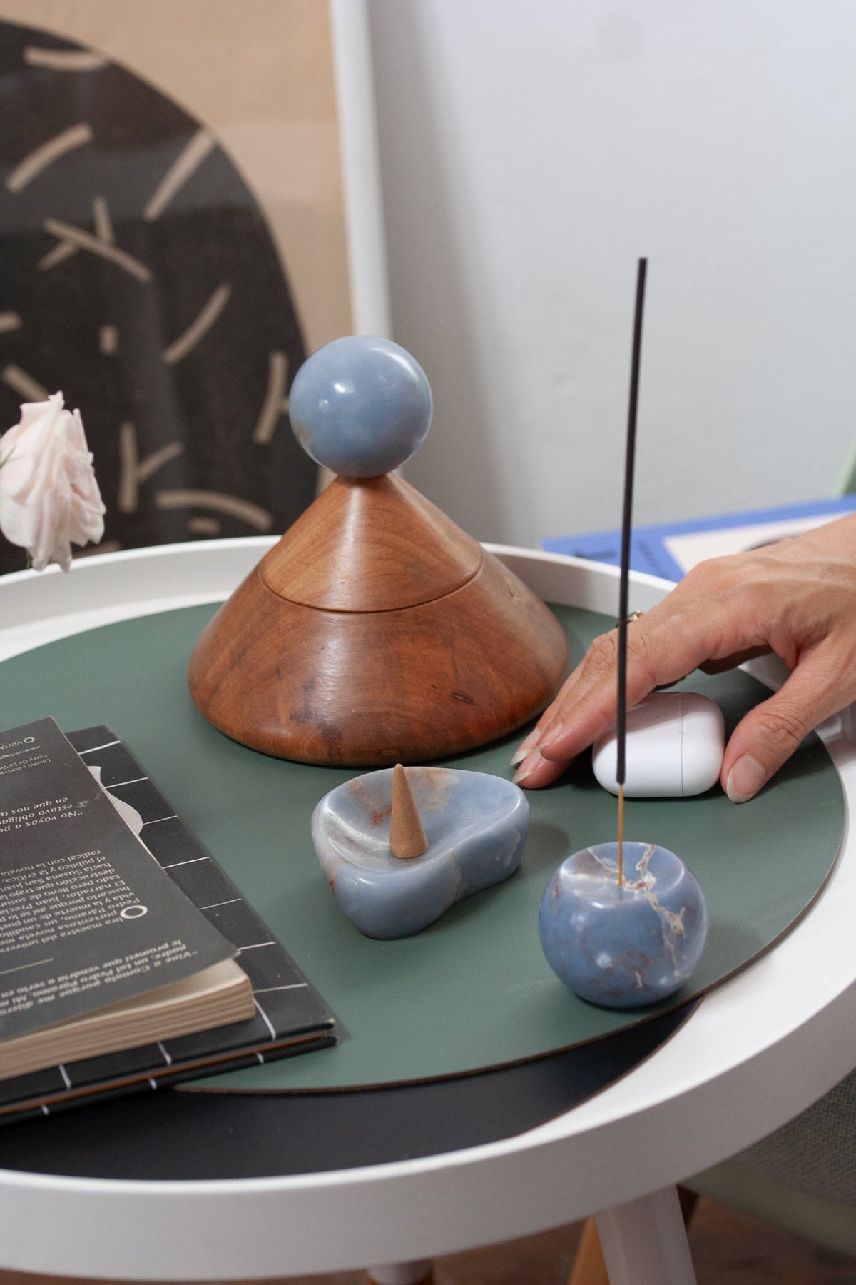 Angelite catchall on a round side table with a burning incense stick and a wooden vessel