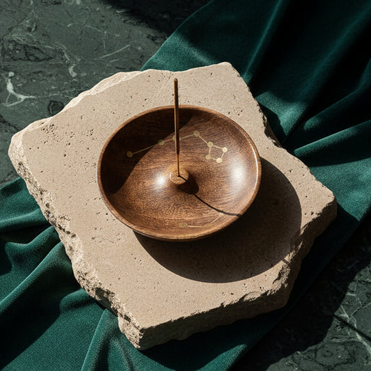 Jyotisha mango wood incense dish with brass constellation inlay on a stone slab, stick burning