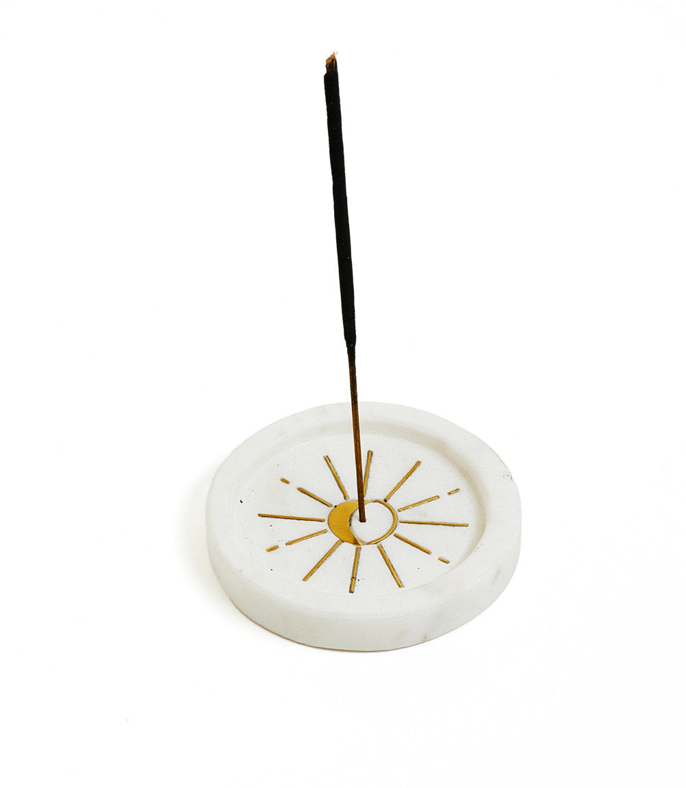 Marble incense holder with brass moon inlay, incense stick upright in the center hole