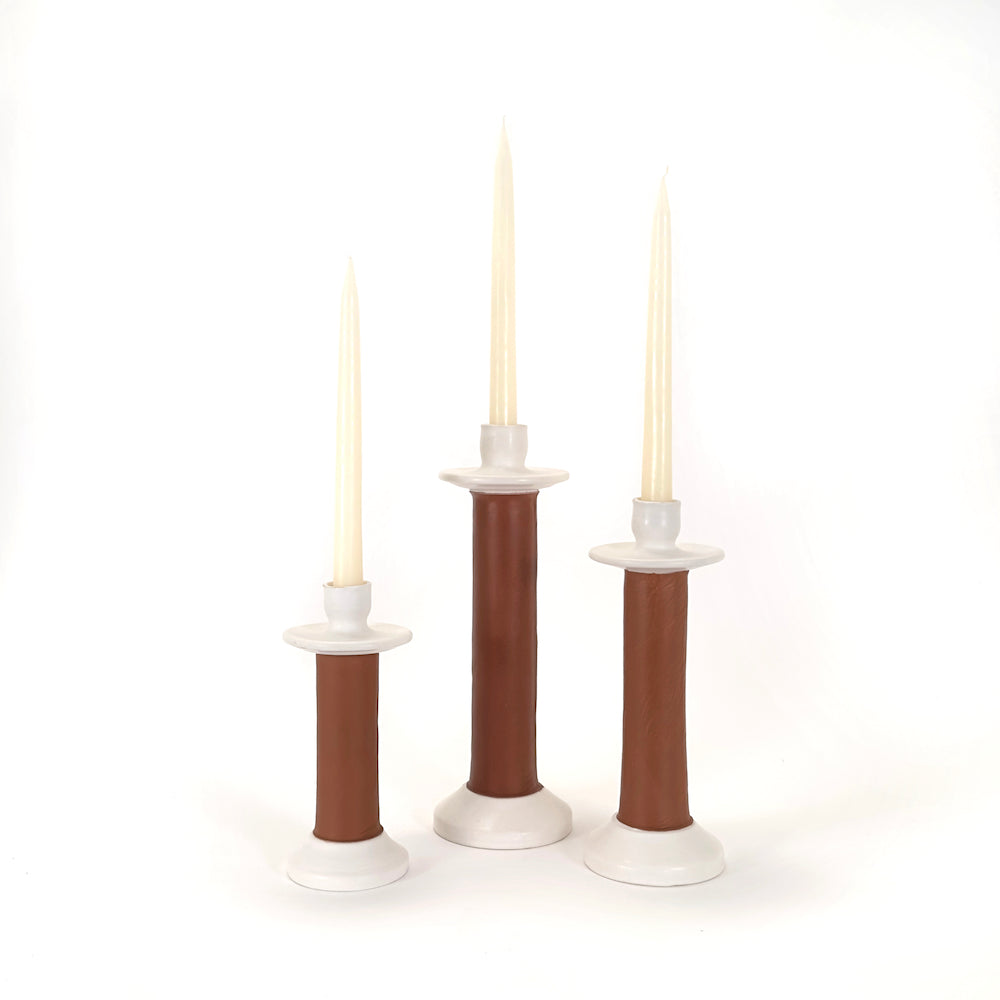 Three leather-wrapped candle holders in graduated heights, each with a taper