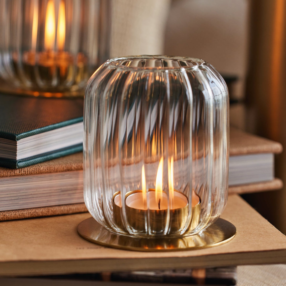 Lit Kira glass lantern standing on a stack of books