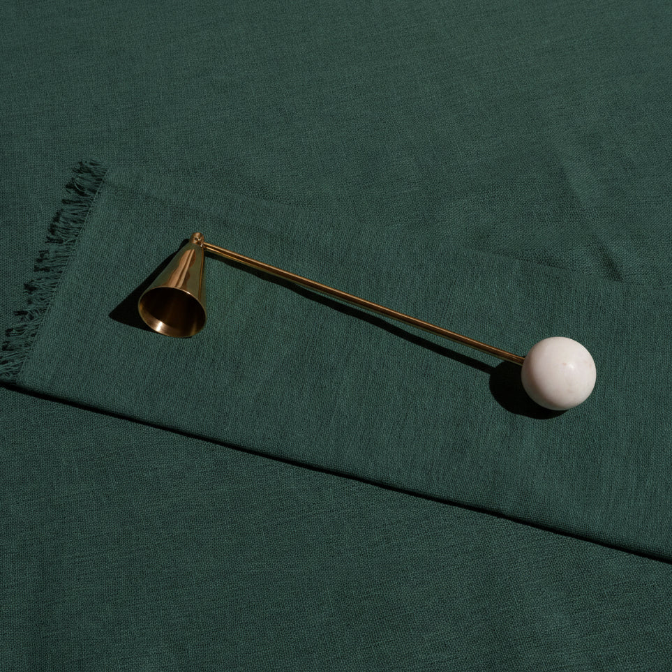 Anka brass candle snuffer with a white marble ball handle on green linen