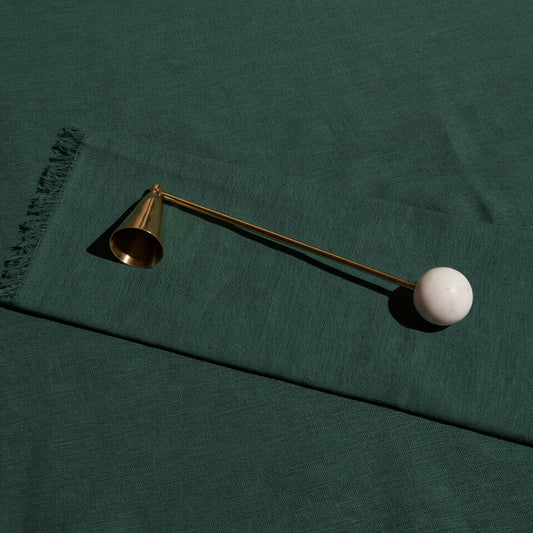 Anka brass candle snuffer with a white marble ball handle on green linen