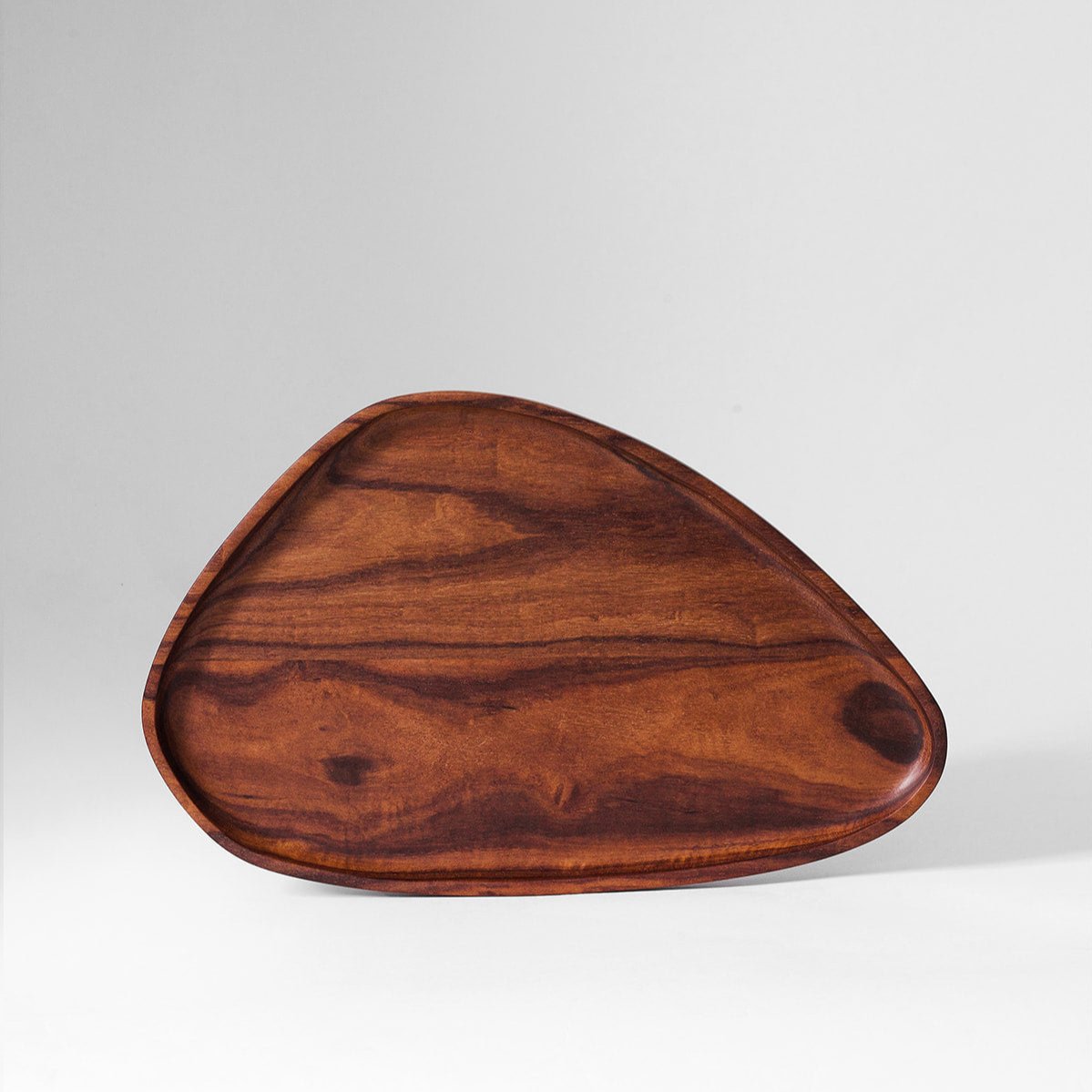 Granadillo leaf tray seen from the side, showing the carved rim and rounded edge