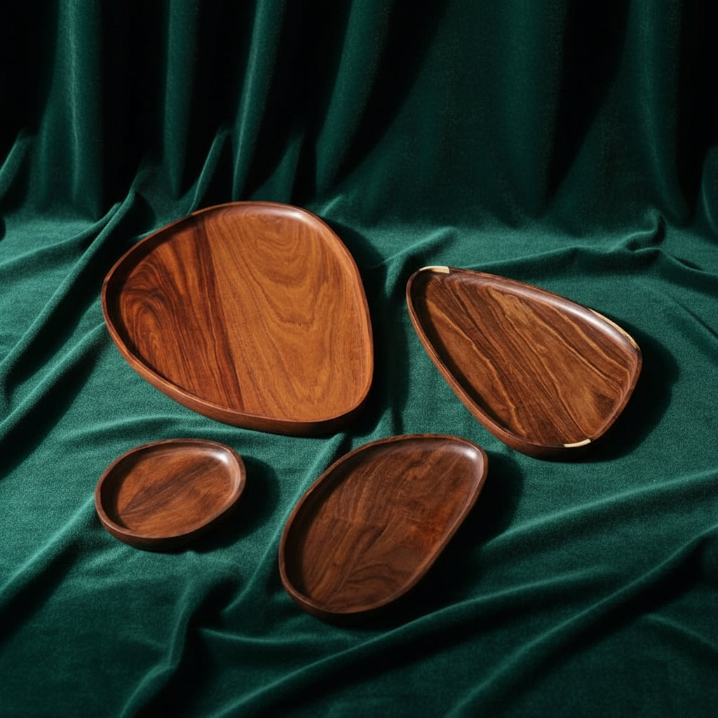 Four granadillo wood leaf trays in graduated sizes arranged on deep green velvet