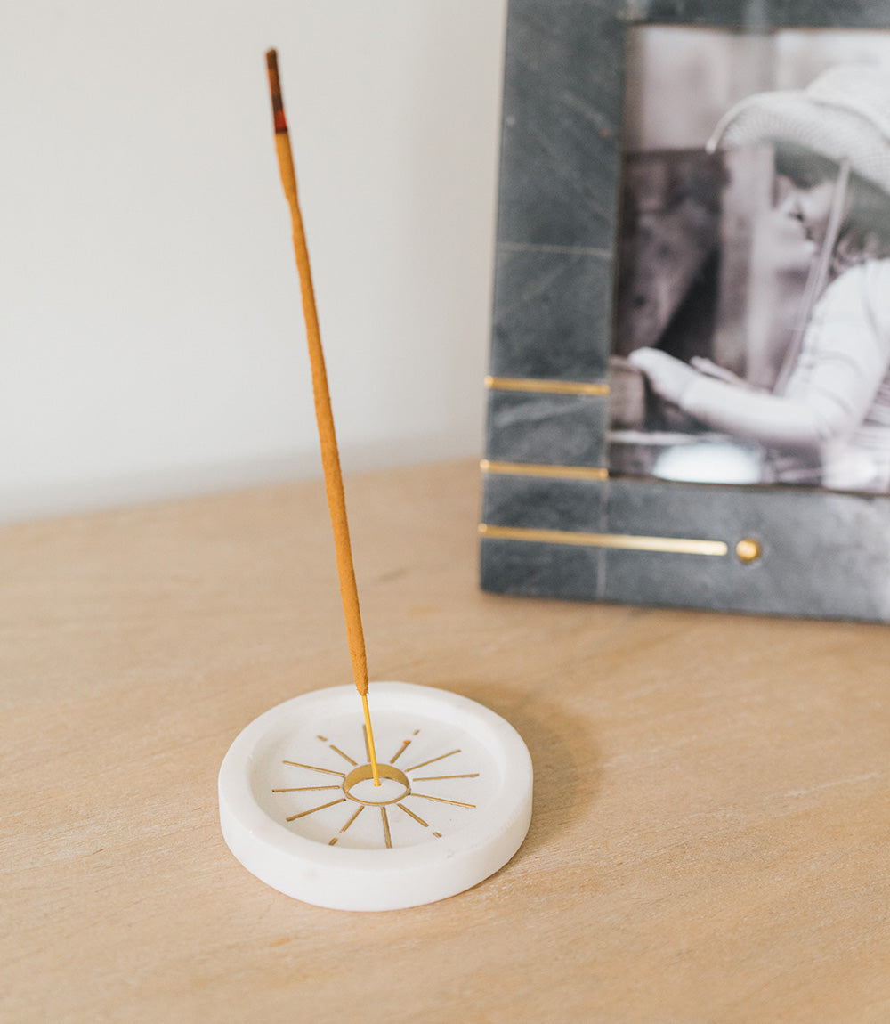 Indukala marble incense holder on a wooden desk beside a framed picture, stick burning