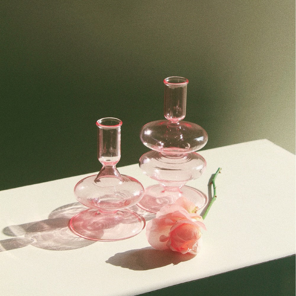 Two pink Siri glass holders in both sizes beside a rose