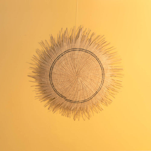 Sun Circle wall disc against a yellow wall, showing the full fringed rim