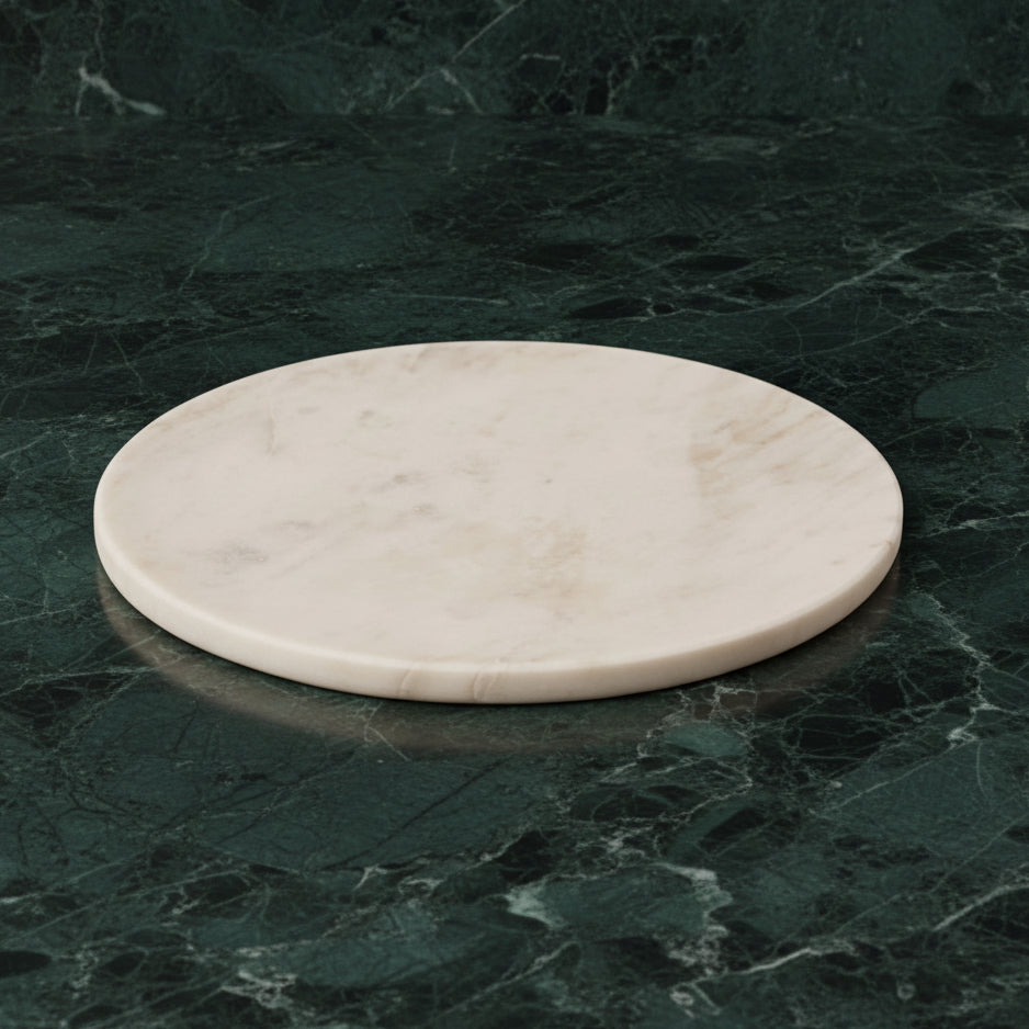 Round white marble platter on dark green marble