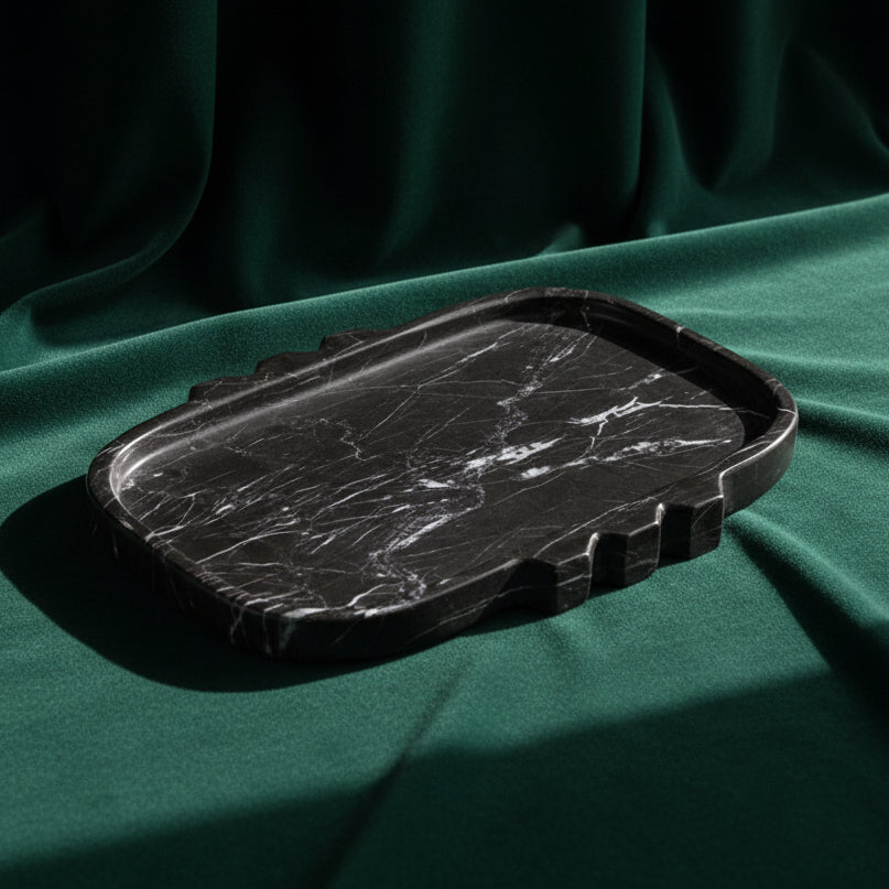 Tauro tray in black marble with white veining and a notched stepped edge, on deep green fabric