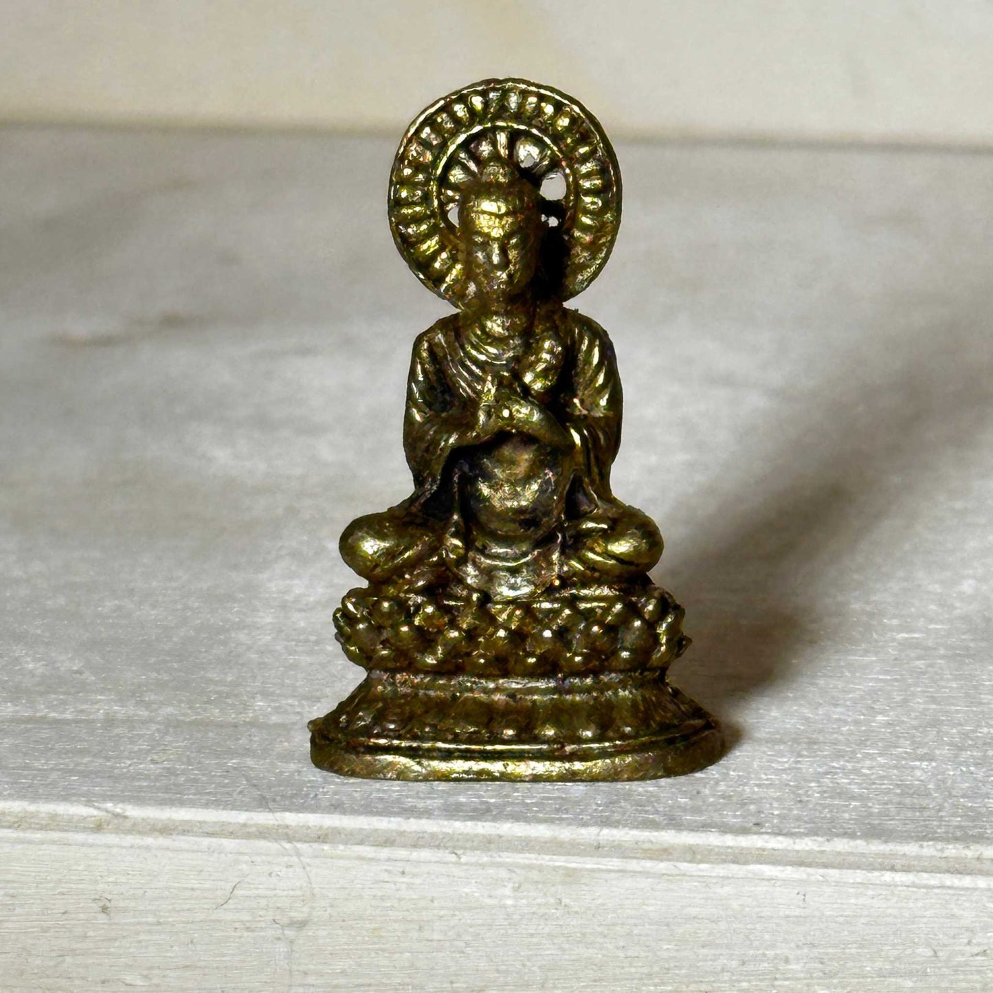 Small brass statue figurine sized to fit in the palm of a hand, product shown with packaging