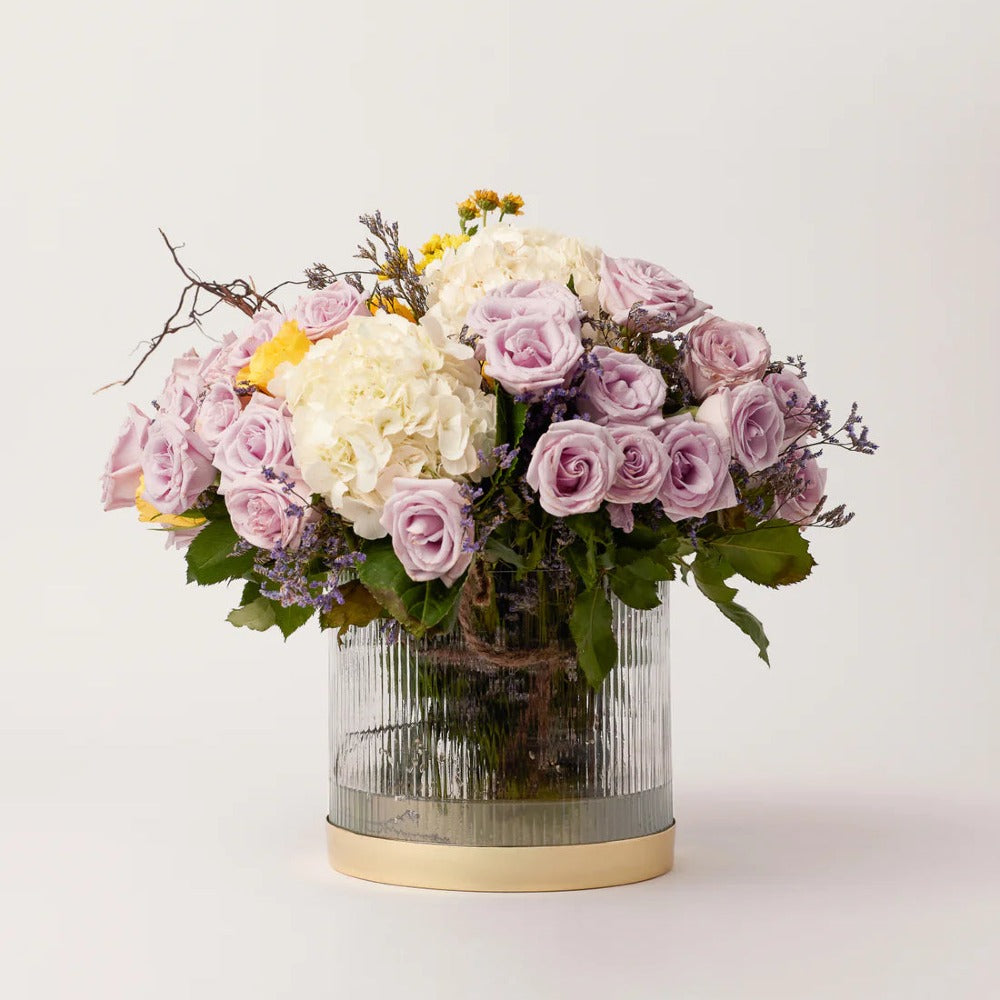 Fluted glass vase holding a full arrangement of roses and hydrangea