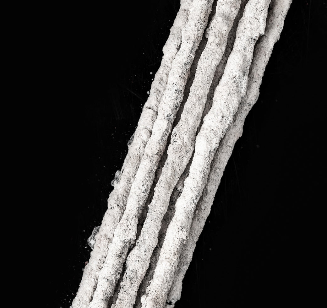 Close-up of the pale hand-rolled Moon Cosmos incense sticks on a black surface