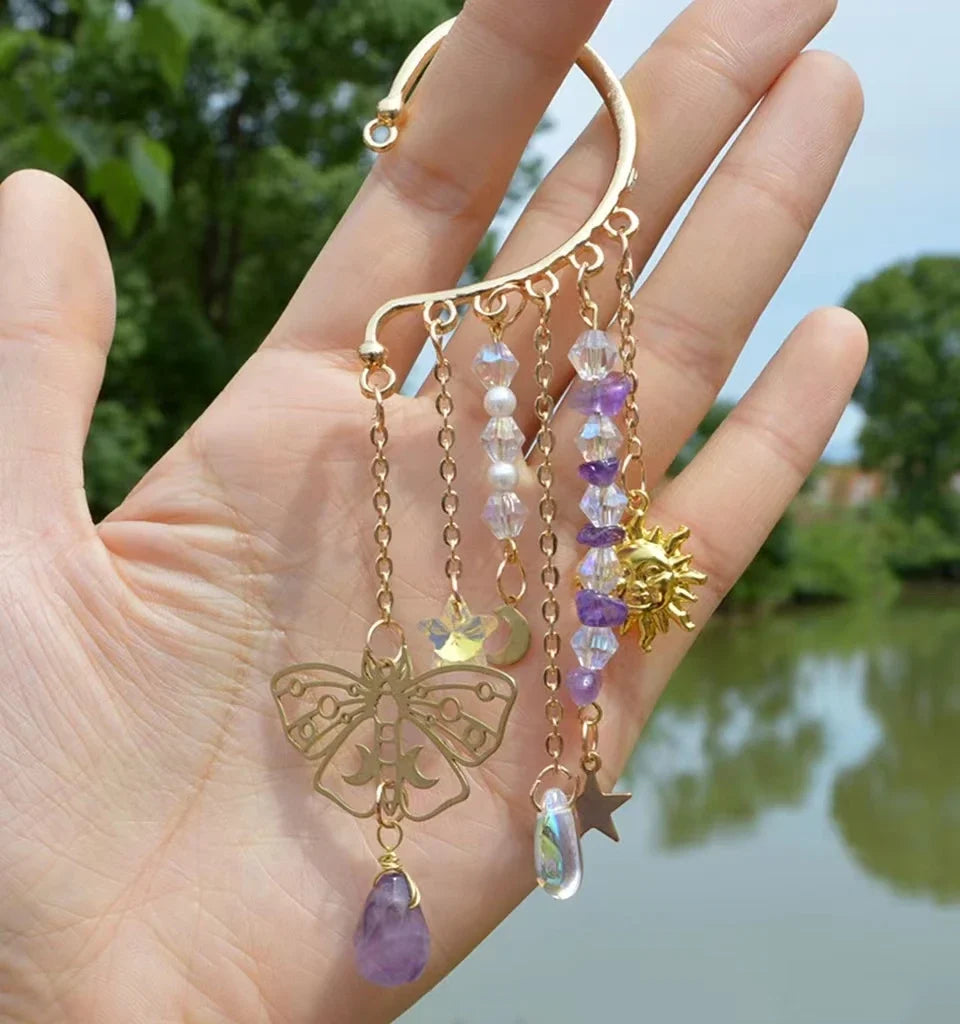 Gold ear cuff earring with sun and moon charms and a long natural quartz crystal drop, worn on one ear — product photo 4