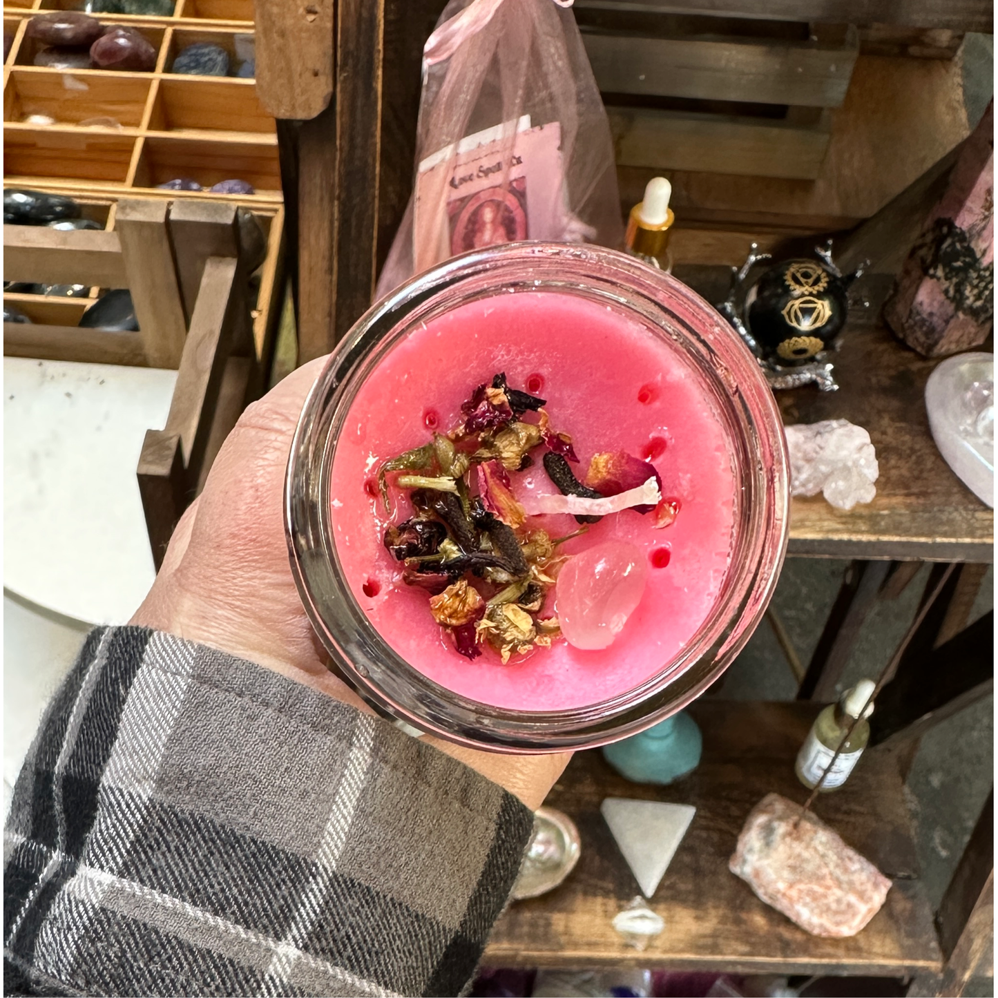 Close-up of the Love Drawing candle showing rose petals and rose quartz on the wax.