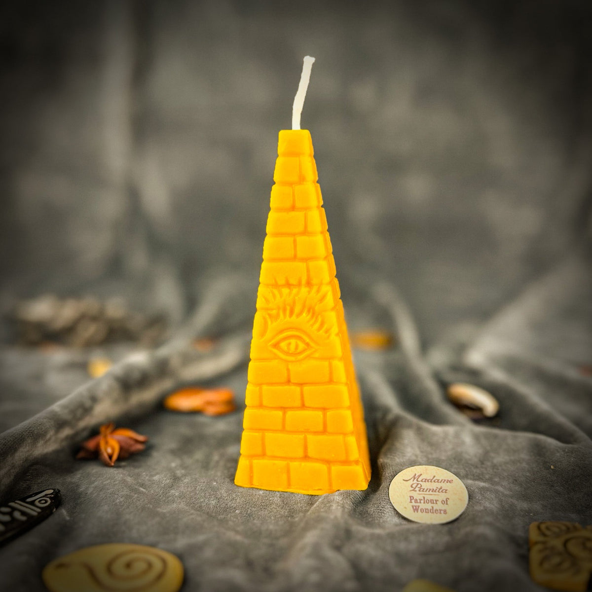 Amber-yellow pyramid candle, the wax translucent enough to glow where the light passes through.