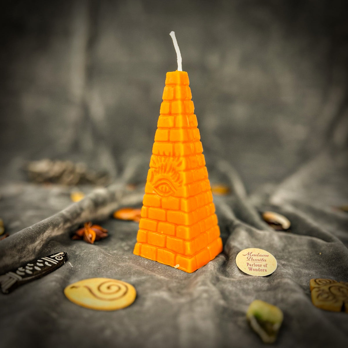 Orange pyramid candle with a long white cotton wick, the Madame Pamita label at its foot.