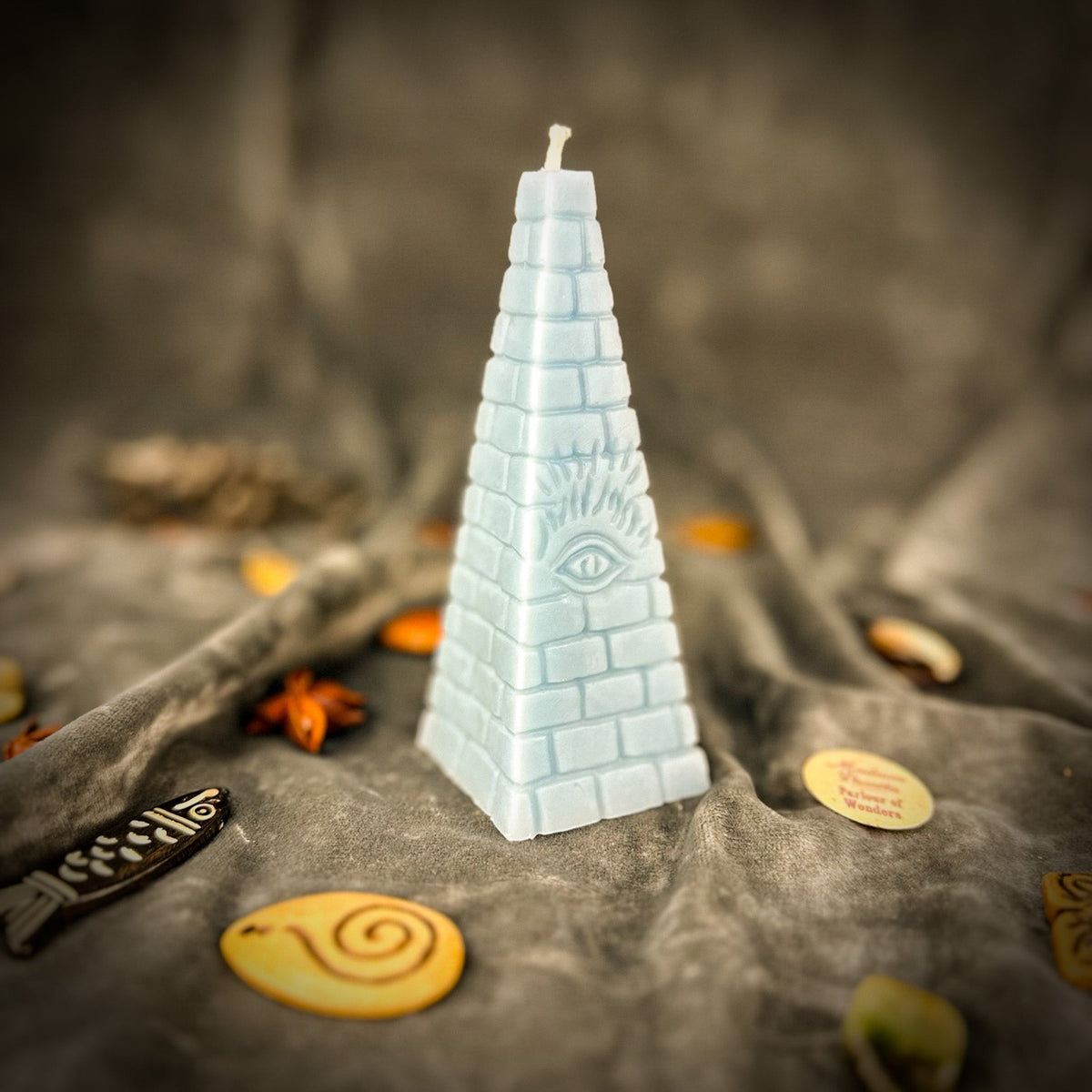 Pale blue pyramid candle, the molded eye barely raised from the surface.