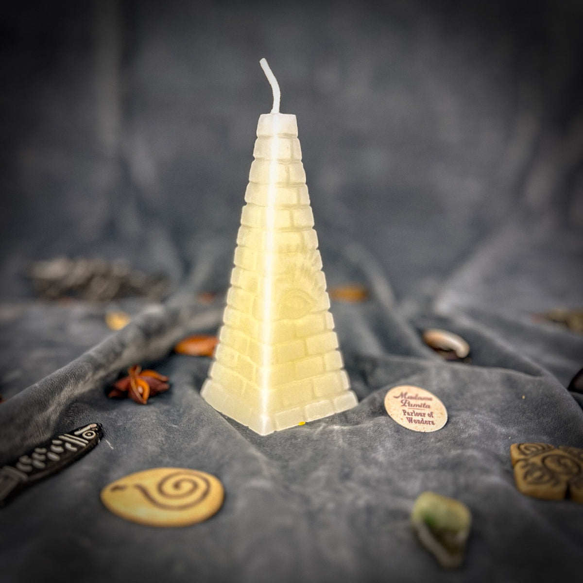 Cream-white pyramid candle, the relief readable only in its shadows.