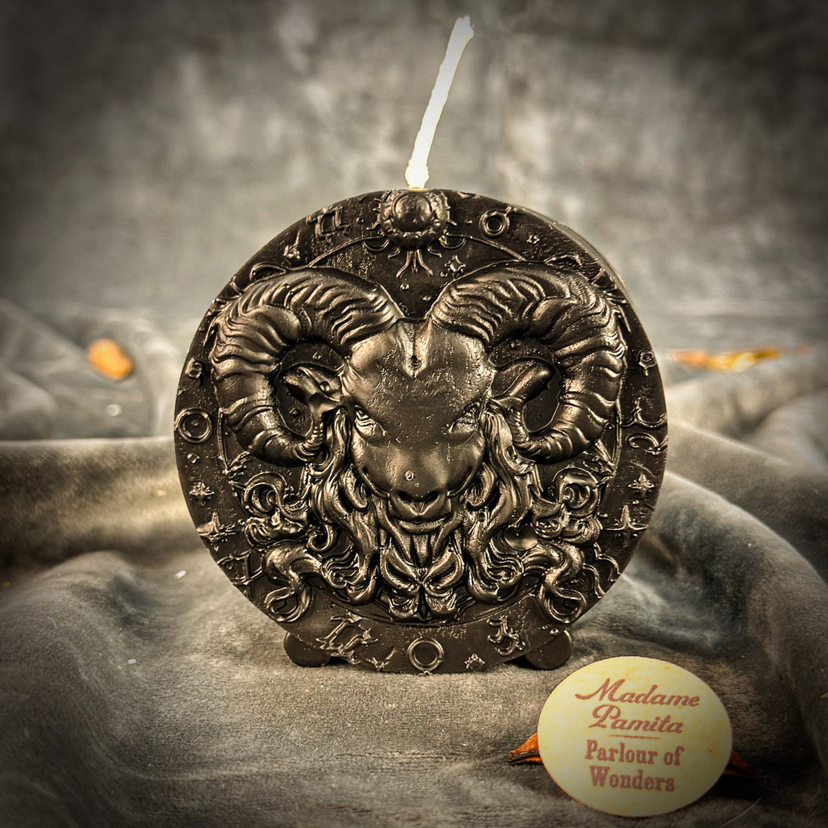 Black Aries medallion candle, horns and fleece showing as highlights on dark wax.