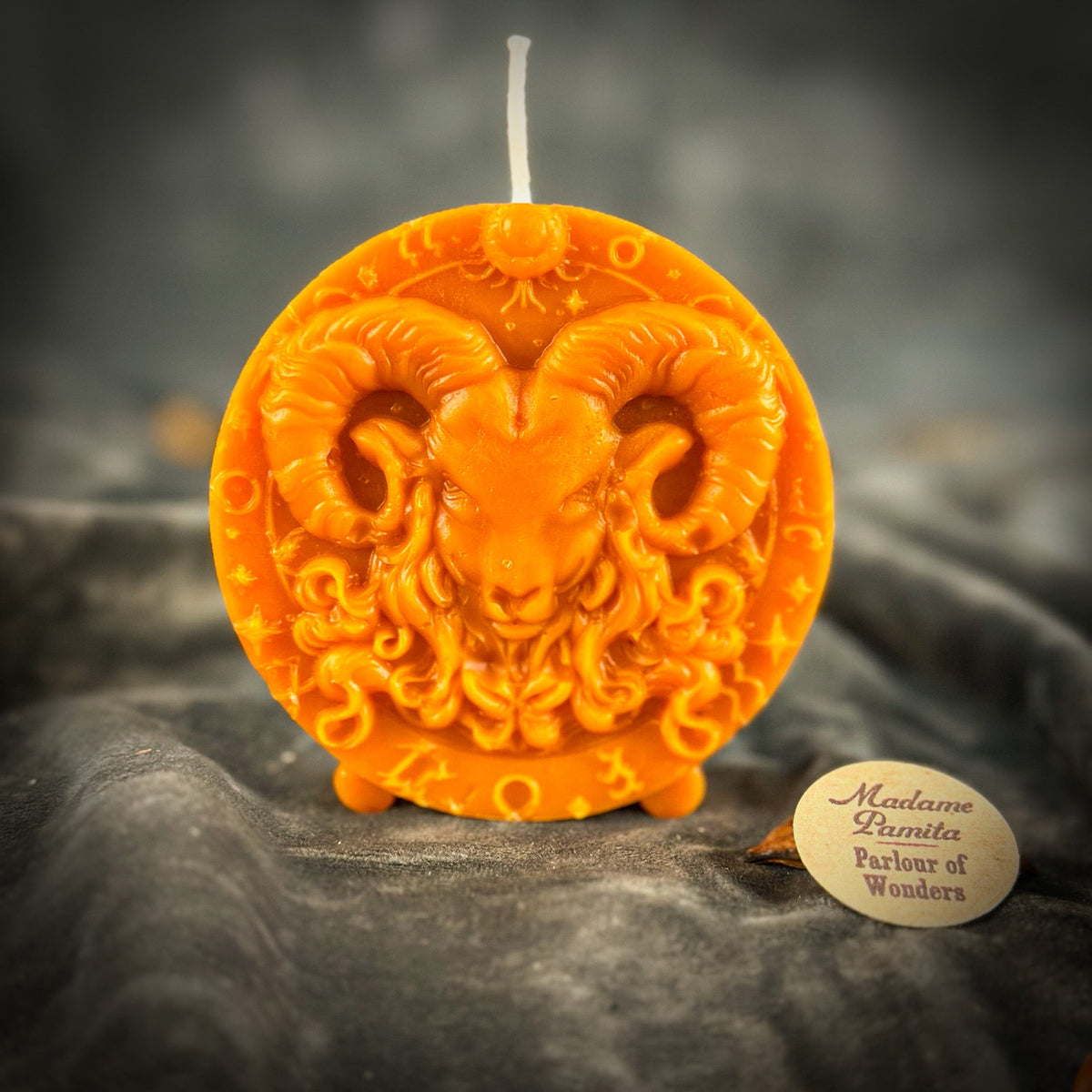 Bright orange Aries medallion candle, the curled horns framing the face.