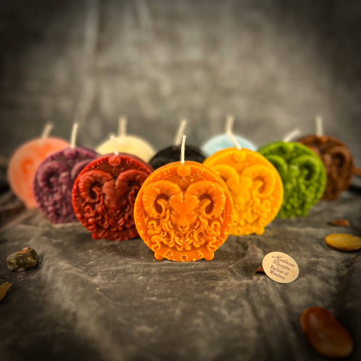 The orange Aries medallion in front of the other colors on gray velvet, the ram's horns catching the light.