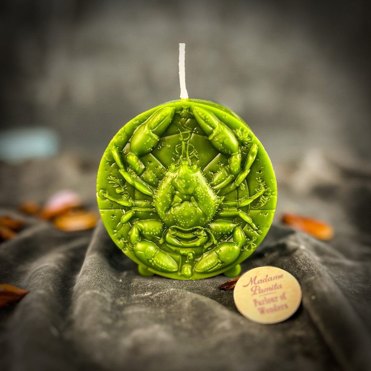 Cancer Crab zodiac spell candle in green on draped gray fabric