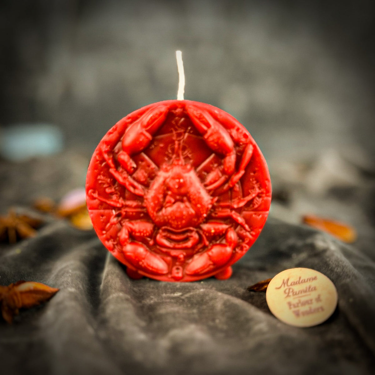 Cancer Crab zodiac spell candle in red on draped gray fabric