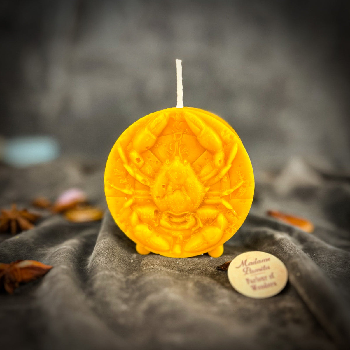 Cancer Crab zodiac spell candle in yellow on draped gray fabric
