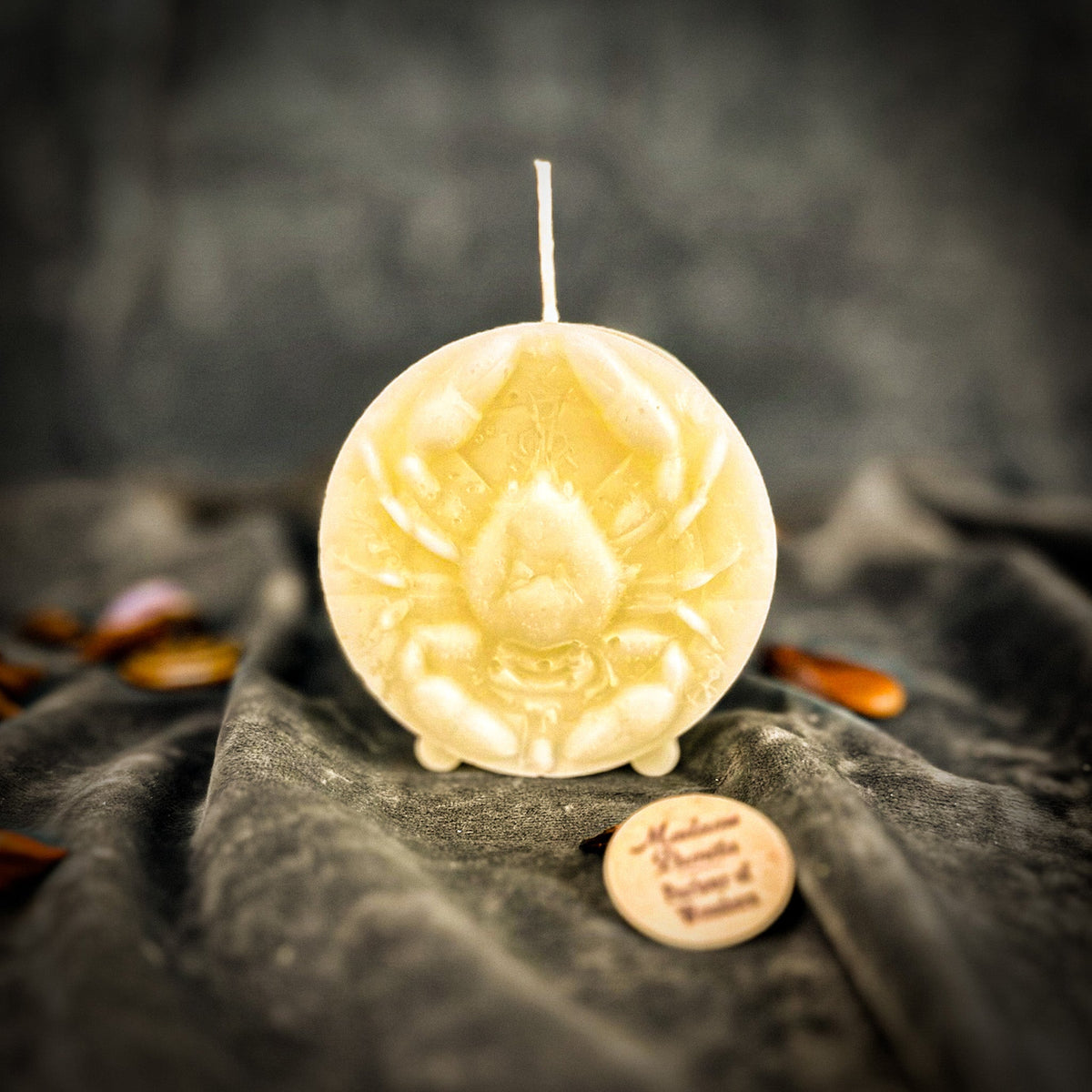 Cancer Crab zodiac spell candle in ivory white on draped gray fabric