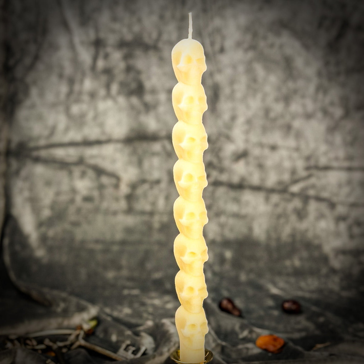 Cream white beeswax skull taper candle showing the stacked skull relief in close detail