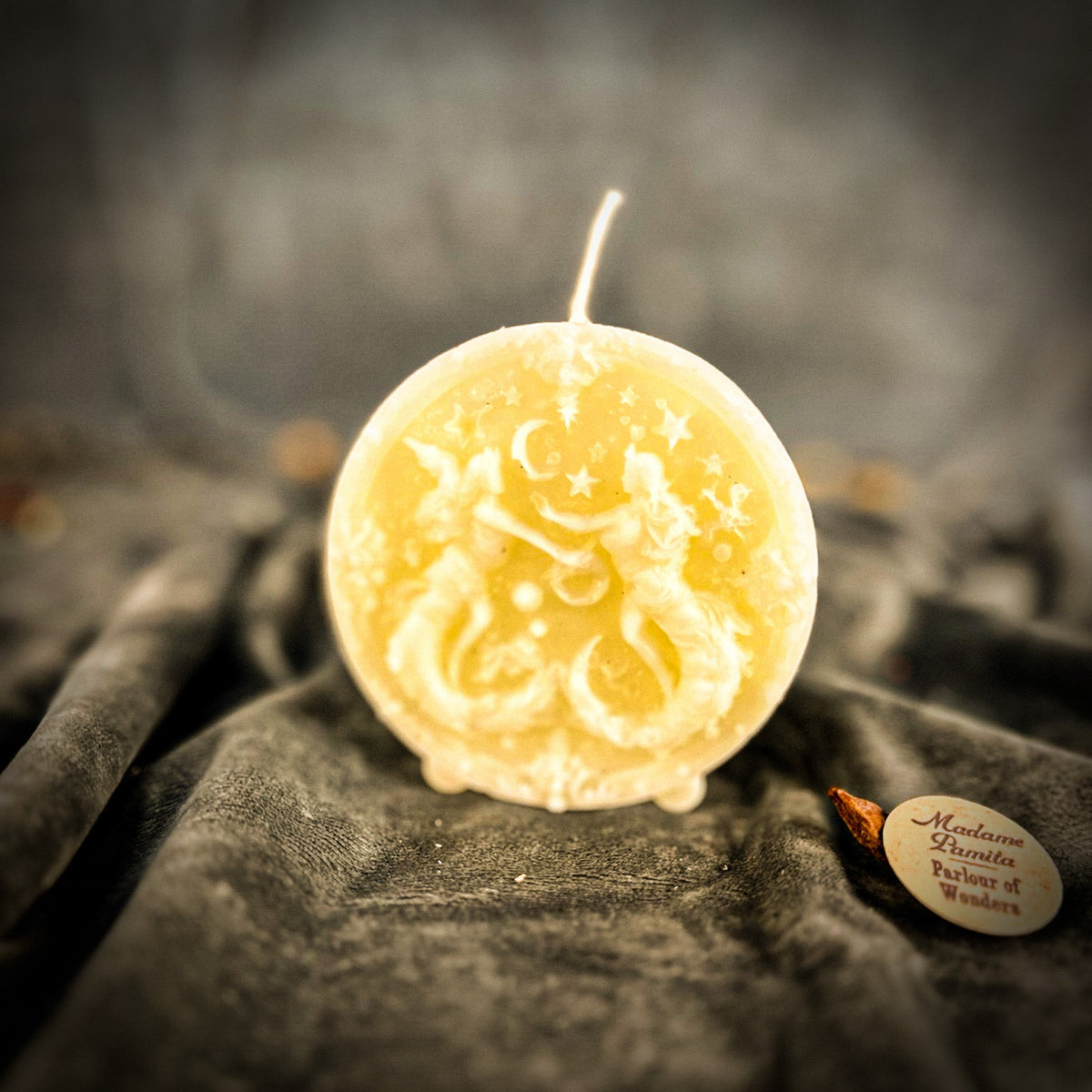 Cream-white Gemini medallion candle, the twins and the star border soft in the pale wax.