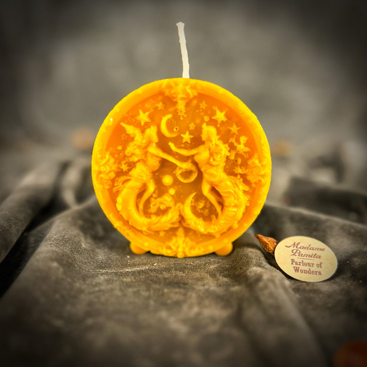 Golden-yellow Gemini medallion candle, translucent enough to glow at the edges.