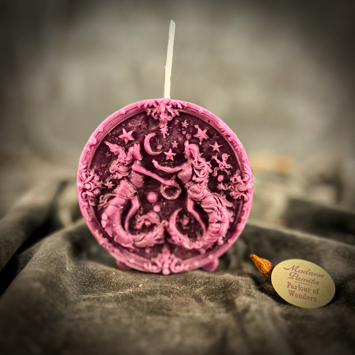 Rose-pink Gemini medallion candle, the border scrollwork sharply cast.