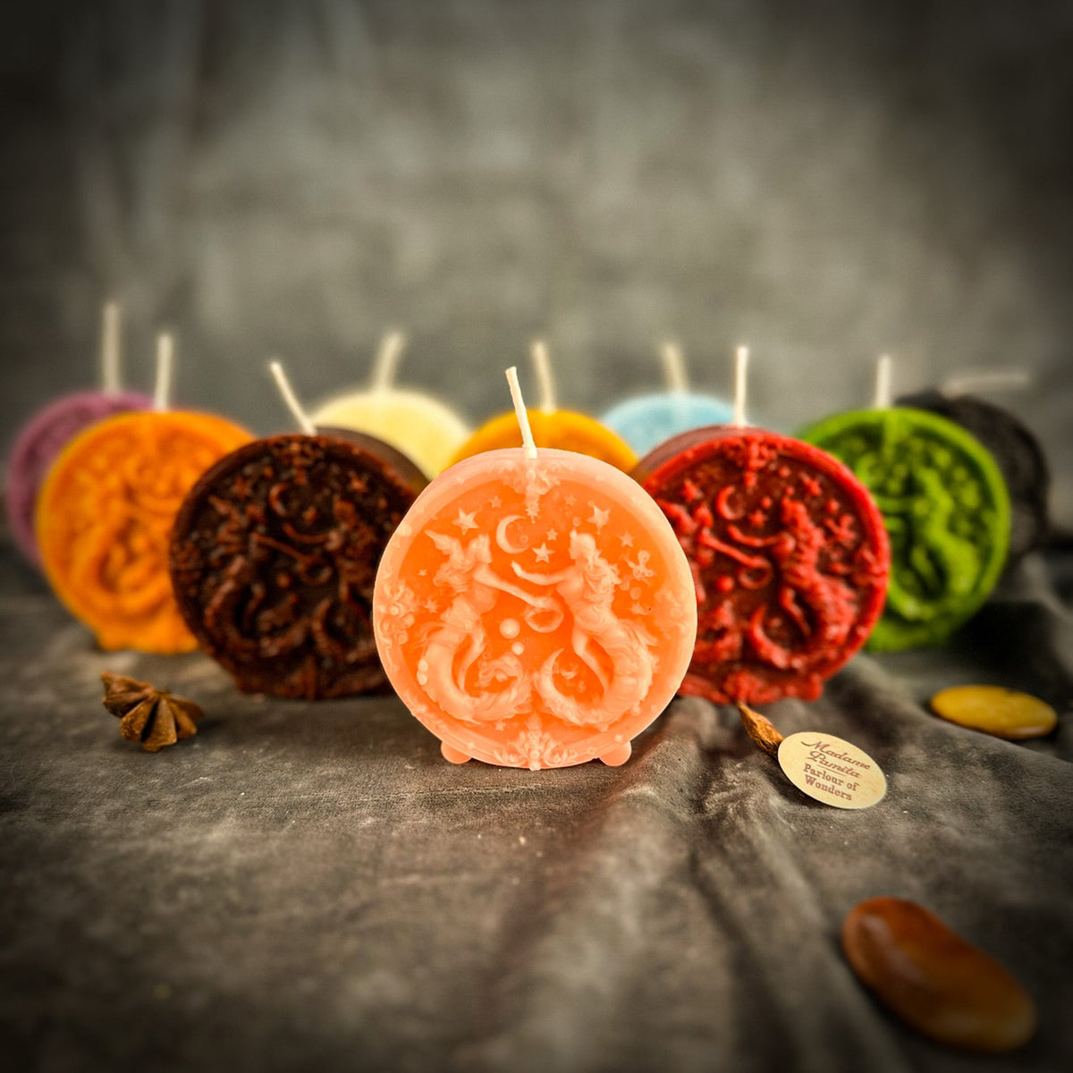 The peach Gemini medallion in front of the other colors on gray velvet, the paired figures picked out in lighter wax.