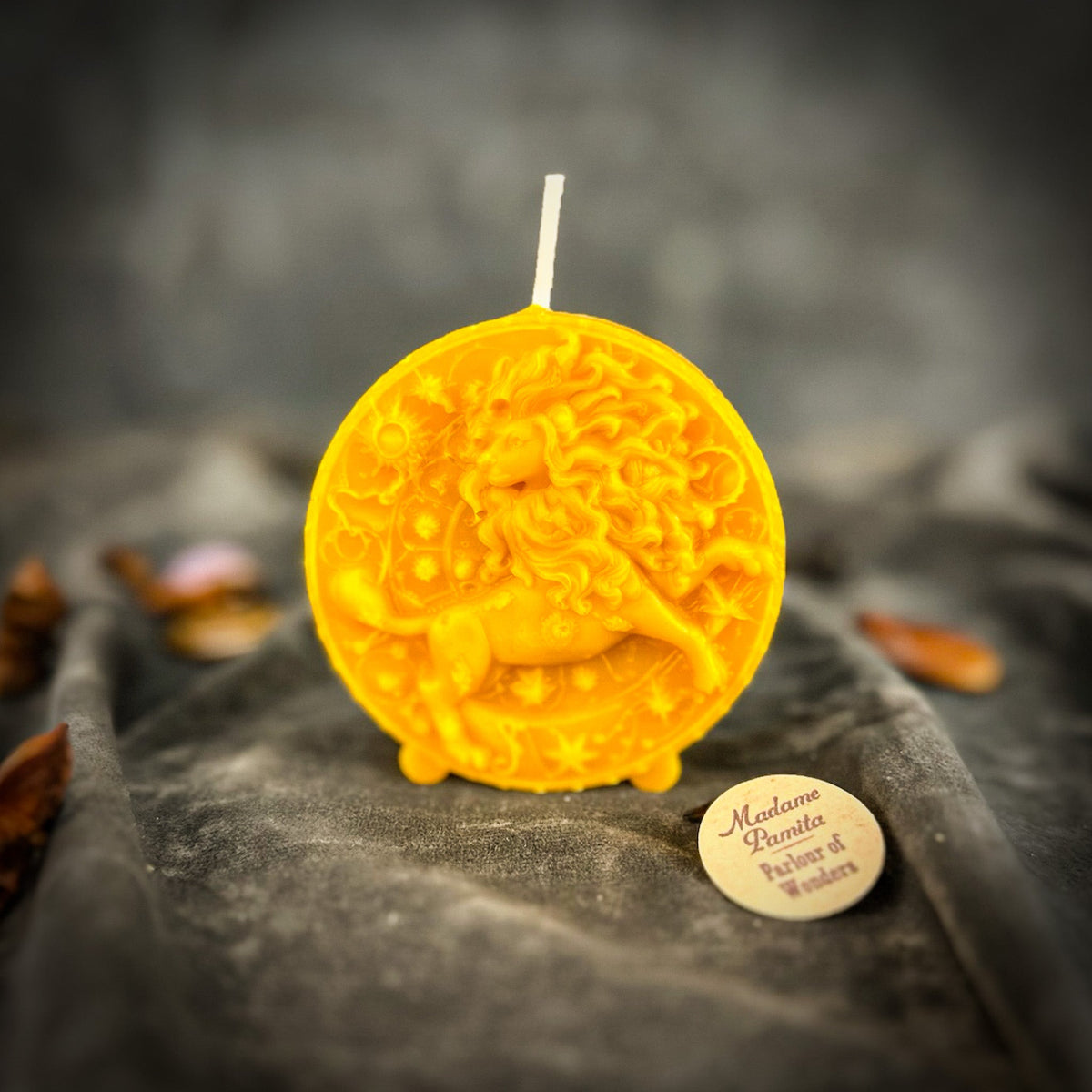 Leo Lion zodiac spell candle in yellow on draped gray fabric