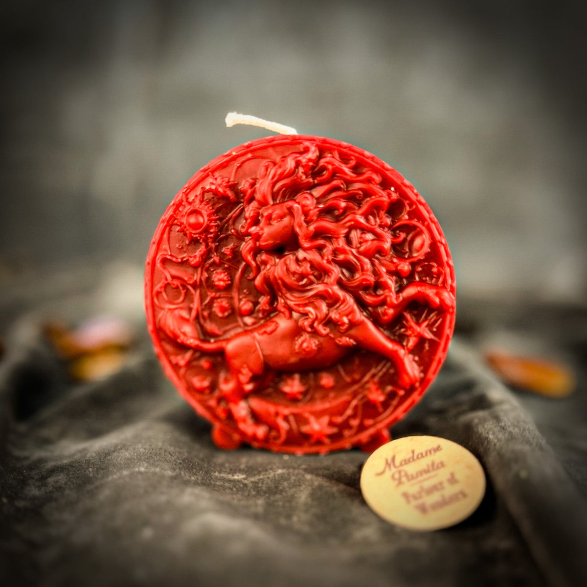 Leo Lion zodiac spell candle in red on draped gray fabric