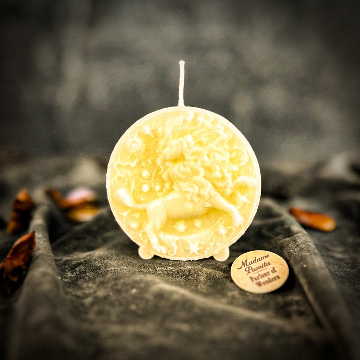 Leo Lion zodiac spell candle in ivory white on draped gray fabric