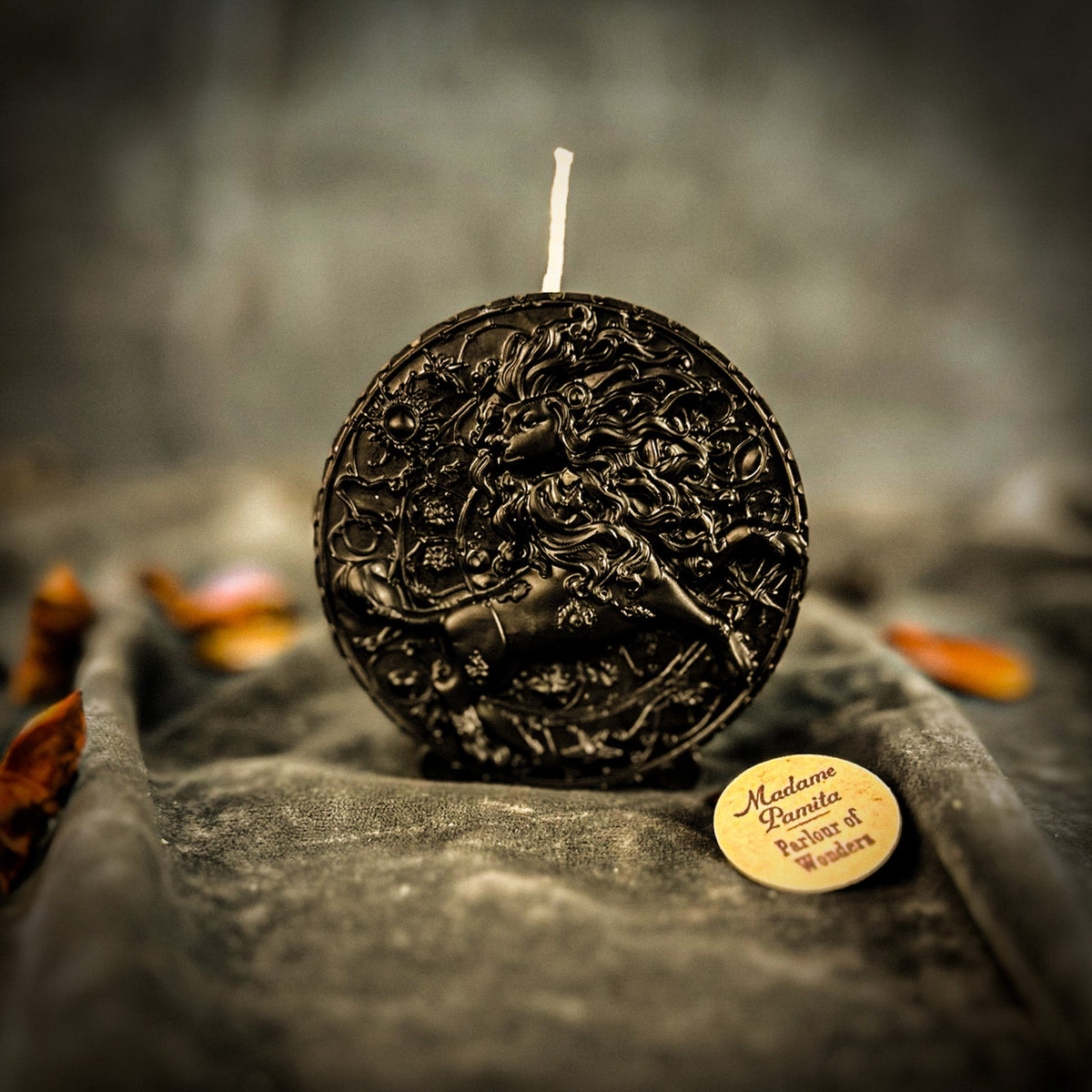 Leo Lion zodiac spell candle in black on draped gray fabric