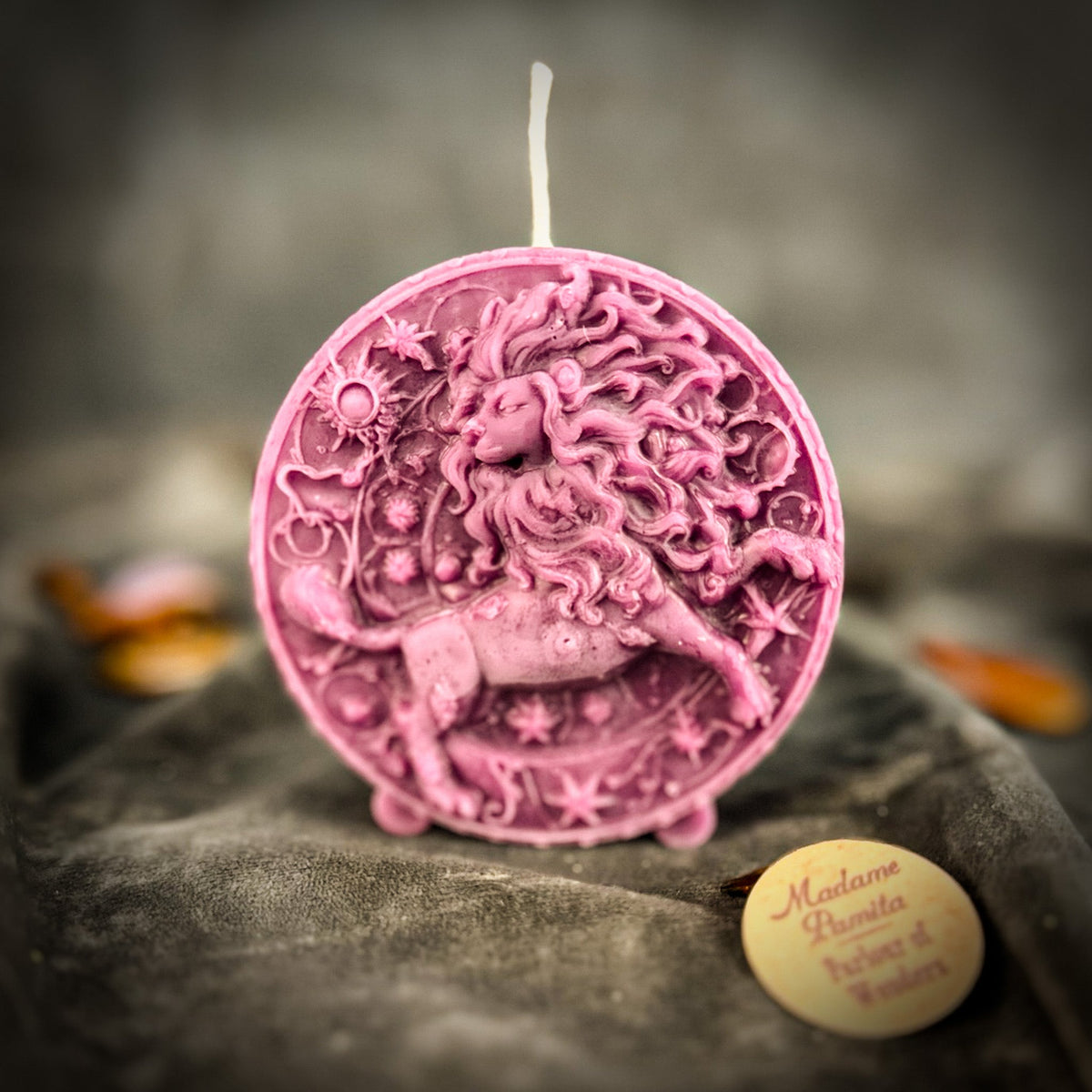 Leo Lion zodiac spell candle in deep pink on draped gray fabric