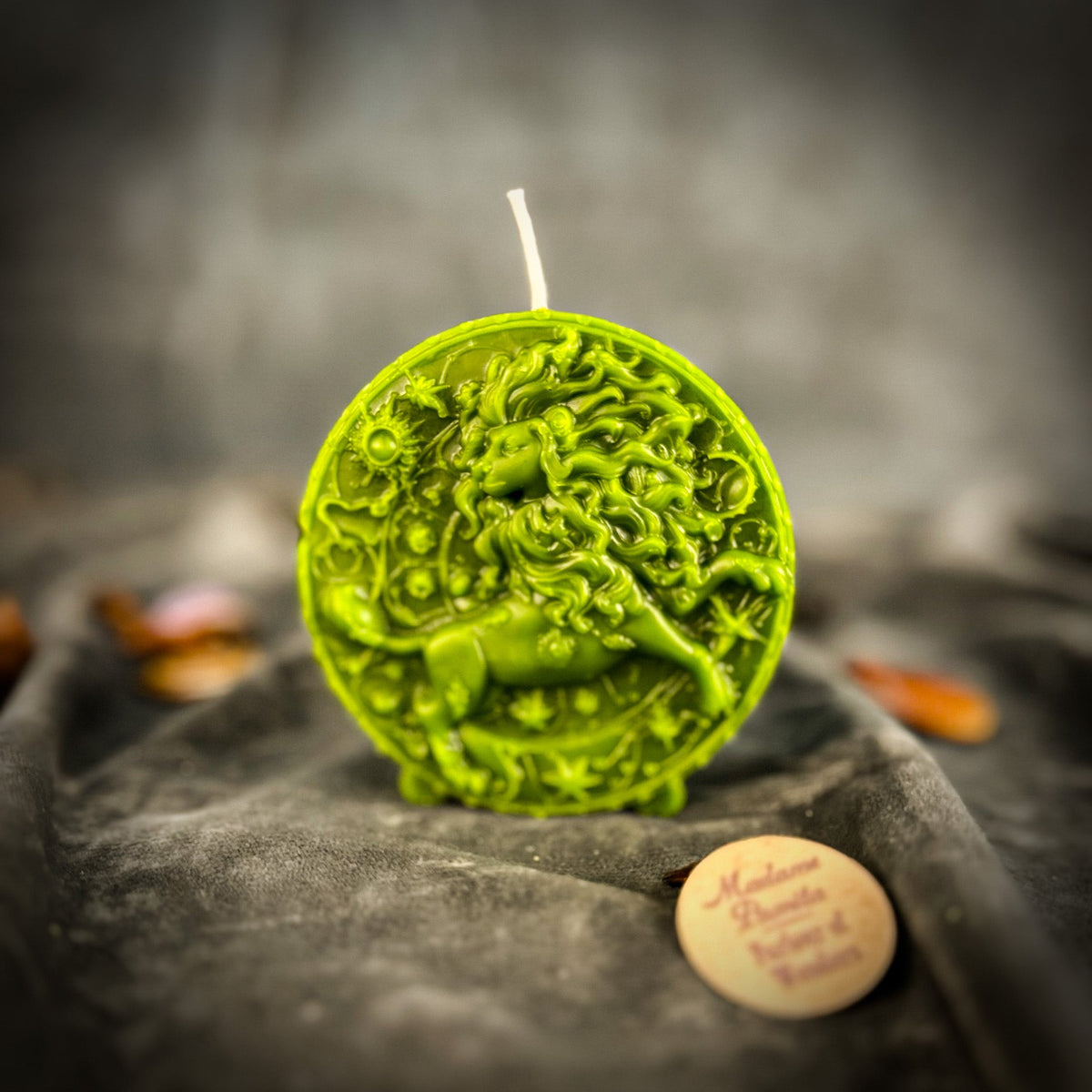 Leo Lion zodiac spell candle in green on draped gray fabric