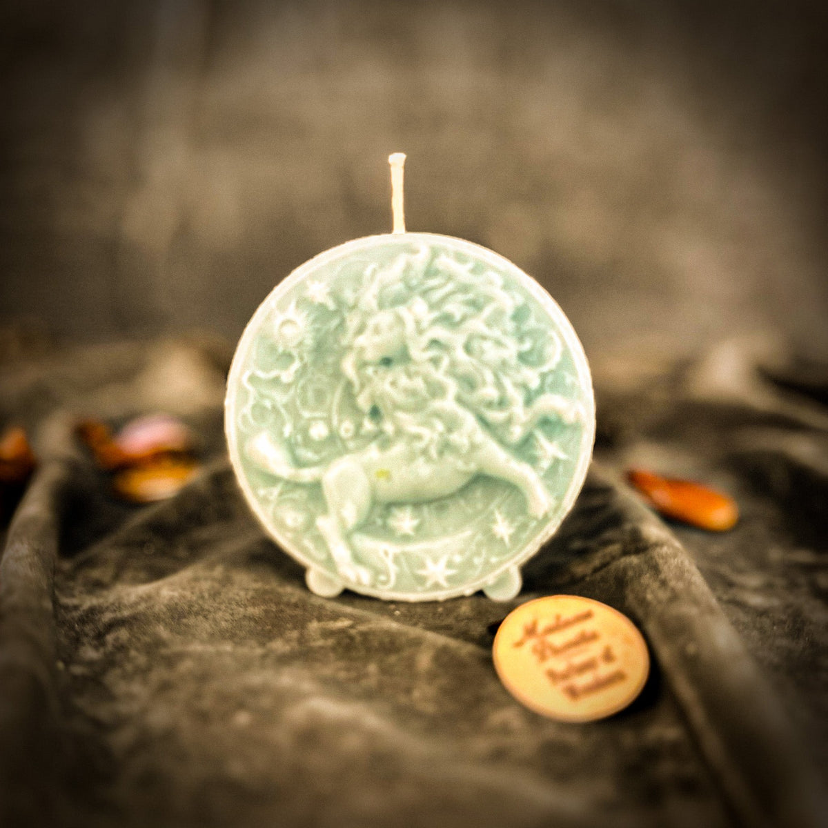 Leo Lion zodiac spell candle in pale white-green on draped gray fabric